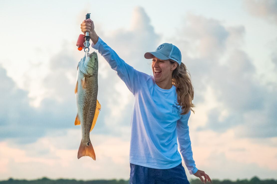 Woman happily holding up a freshly caught fish in Matagorda Bay Nature Park.