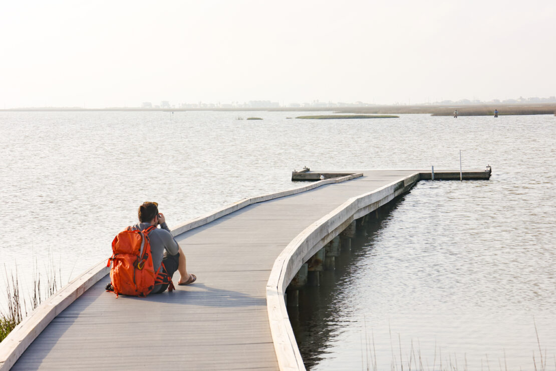 Photographer sitting on a pier in the wetlands of Matagorda Bay Nature Park.