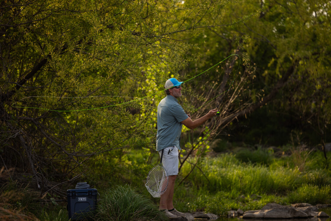 Man casting a fly fishing line on the bank of the river at Pedernales River Nature Park.